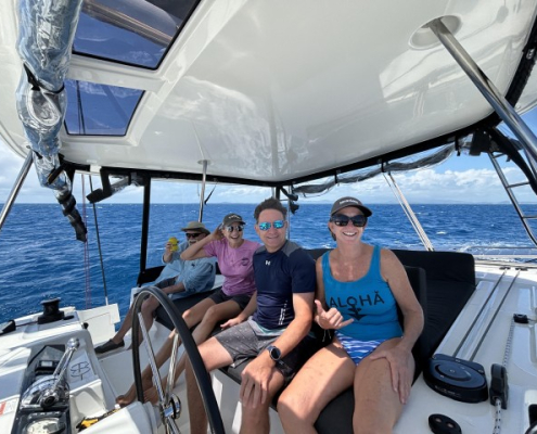 Group enjoying a sunny day sailing on a yacht in the ocean, highlighting leisure and boating adventure.